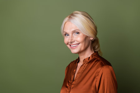 Photo portrait of lovely senior lady toothy smile chief manager wear trendy satin brown garment isolated on khaki color backgroundの写真素材