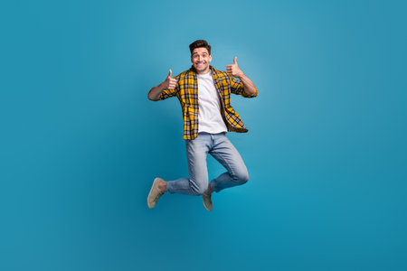 Full size body photo of young funky positive overjoyed guy thumbs up jumping showing good feedback...