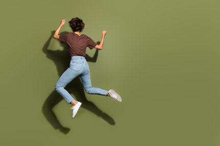 Full body photo of attractive young woman back view running jump dressed stylish brown clothes...