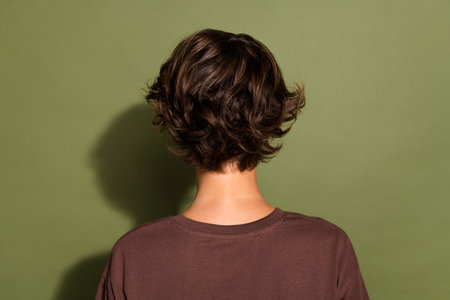 Back rear view photo of gorgeous girl with bob hairstyle dressed dressed t-shirt turned with her back isolated on khaki color backgroundの写真素材