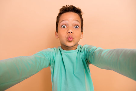 Photo of small funky person take selfie recording video pouted lips kiss isolated on beige color backgroundの写真素材