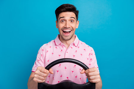 Photo of astonished crazy cheerful person open mouth arms hold steering wheel isolated on blue color...