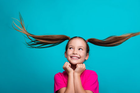 Portrait of good mood girl fluttering tails dressed pink t-shirt dreamy look at offer empty space isolated on turquoise color backgroundの写真素材