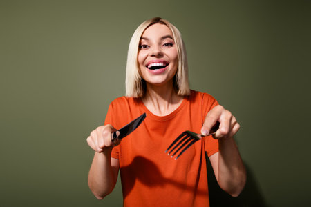 Photo of funny hungry lady bob blonde hair hold metal fork knife wait handmade mommy meal cutting pieces isolated on khaki color backgroundの写真素材