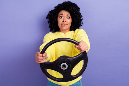Portrait of scared person with chevelure wear pullover hold steering wheel biting lips get in crash isolated on purple color backgroundの写真素材