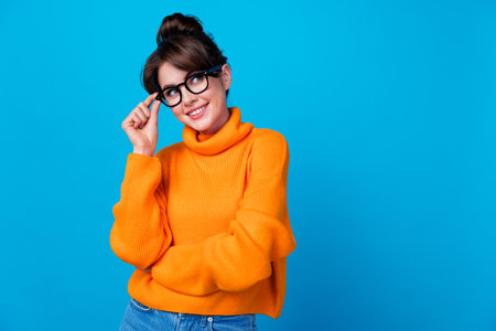 Photo of dreamy adorable lady wear knitted pullover arm hand spectacles looking empty space isolated blue color backgroundの写真素材