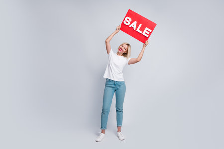 Full size photo of good mood nice woman dressed white t-shirt hold placard over head announcing sale isolated on white color backgroundの写真素材