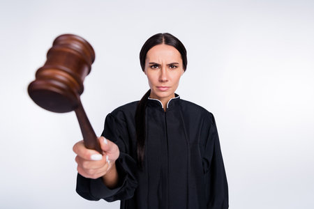 Photo of serious woman judge attorney punish you guilty using gavel wear black robe isolated on white color backgroundの写真素材