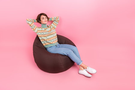 Full length body photo of lying bean bag comfortable place for sleeping after courses take nap girl isolated on pink color backgroundの写真素材
