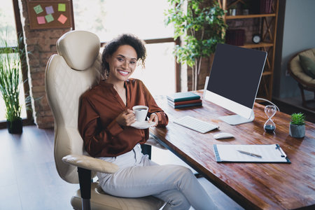 Photo of stunning positive company founder lady sitting chair hold aroma coffee cup workstation business center insideの写真素材