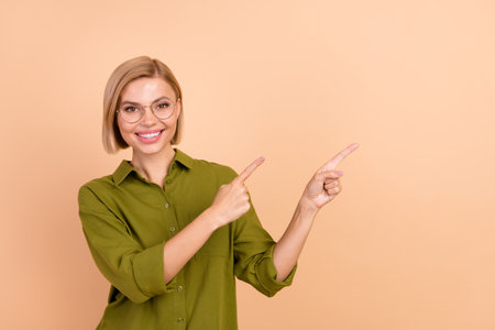 Portrait of nice girl with straight hairdo wear khaki shirt directing at proposition empty space isolated on pastel color backgroundの写真素材