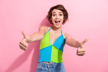 Photo of impressed funky lady wear green blue tank top showing two thumbs up isolated pink color backgroundの写真素材