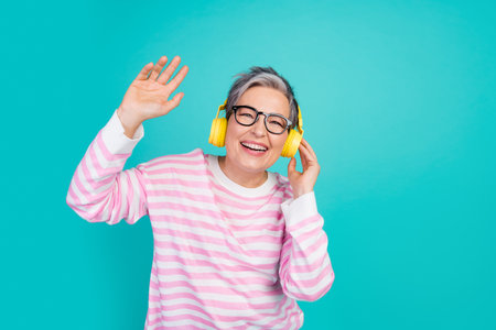 Photo of good mood excited woman dressed pink pullover listening melody earphones empty space isolated teal color backgroundの写真素材