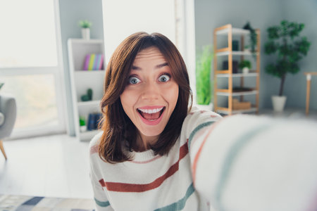 Portrait of astonished positive person make selfie open mouth unbelievable reaction modern interior apartment insideの写真素材