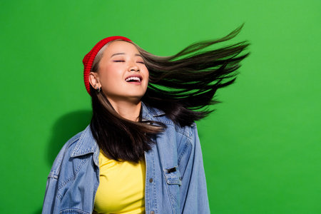Photo portrait of attractive young woman fluttering hair enjoy procedure wear trendy jeans clothes isolated on green color backgroundの写真素材