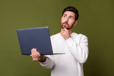 Photo of minded nice man wear stylish white clothes use modern netbook look up empty space isolated on khaki color backgroundの写真素材