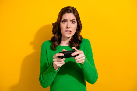 Photo of worried nervous girl addicted gamer competing video game online isolated on yellow color backgroundの写真素材