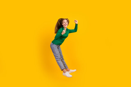 Full body size photo of funky teenage brown haired model girl jumping high raised fists up winner...