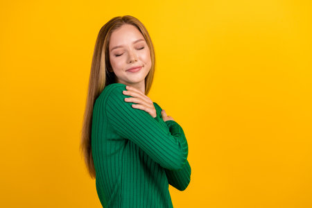 Profile photo of pretty lovely girl closed eyes hands embrace shoulders empty space isolated on yellow color backgroundの写真素材