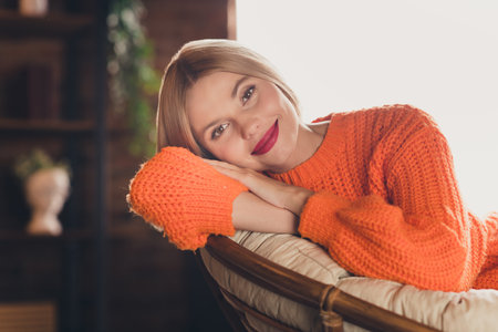 Portrait of positive peaceful adorable girl sitting comfy armchair enjoy moment pastime apartment insideの写真素材