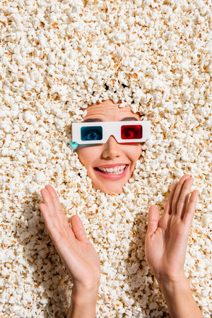 Vertical above view photo of positive cheerful lady toothy smile watch movie 3d glasses arms clapping face isolated on popcorn backgroundの写真素材