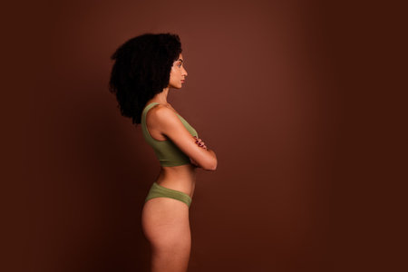 No filter side studio photo of pretty serious woman wear lingerie arms folded looking empty space isolated brown color backgroundの写真素材