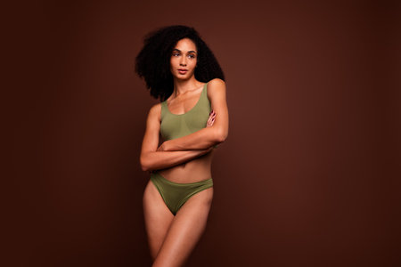 No filter studio photo of thoughtful dreamy woman wear lingerie arm folded looking empty space isolated brown color backgroundの写真素材