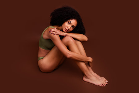 Photo of gorgeous girl no filter thin body hugging knees accepting herself loving imperfections naturality isolated brown color backgroundの写真素材