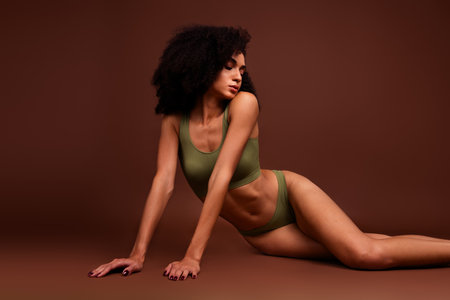 Photo of adorable lovely lady no retouch body with imperfections accepting herself sitting floor isolated on brown color backgroundの写真素材