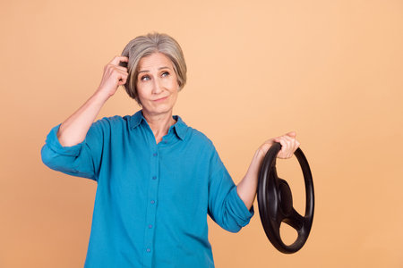 Photo of minded confused woman dressed blue shirt holding steering wheel look empty space scratch...