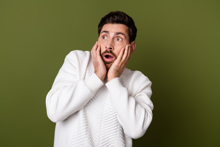 Photo of anxious embarrassed man have problem trouble watch empty space isolated on khaki color backgroundの写真素材