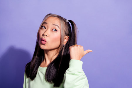 Photo of astonished woman with dyed hair wear sweatshirt staring indicating at discount empty space isolated on purple color backgroundの写真素材