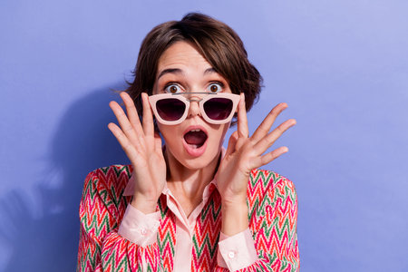 Portrait of speechless girl wear shirt fingers touch stylish sunglass staring at unbelievable sale isolated on blue color backgroundの写真素材
