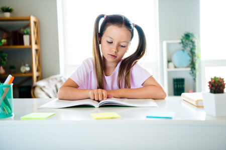 Photo of focused concentrated intelligent girl read attentive book morning bright interior house insideの写真素材