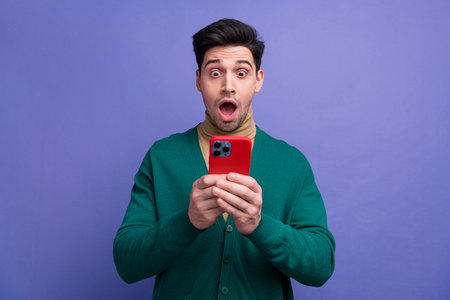 Photo of attractive astonished man wear stylish green clothes read unexpected unbelievable news isolated on purple color backgroundの写真素材