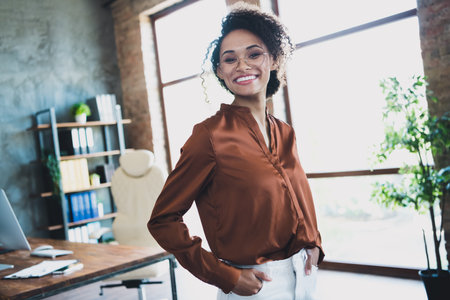 Portrait of positive pretty representative lady put hands pockets posing toothy smile spacious modern workplace insideの写真素材