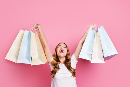 Photo portrait of celebration new collection woman shopaholic raised arms gift packages screaming isolated on pink color backgroundの写真素材