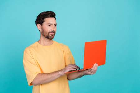 Photo of young freelancer brunet man working remotely at every place he want just using netbook isolated on aquamarine color backgroundの写真素材