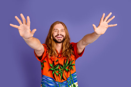 Photo of funny positive person with beard long hairstyle dressed print shirt stretching palms to you isolated on violet color backgroundの写真素材