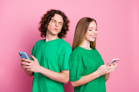 Photo youth couple relationships problems using smartphone looking jealousy dislike chatting girlfriend isolated on pink color backgroundの写真素材