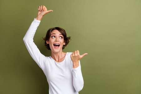 Portrait of funny cute girl showing empty space announcement new product sale offer isolated khaki green color backgroundの写真素材