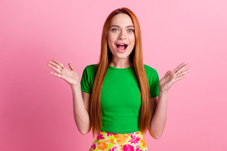 Portrait of overjoyed funky girl with redhead hair wear stylish top raising palms scream open mouth isolated on pink color backgroundの写真素材