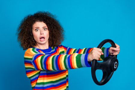 Photo of attractive young woman confused driving terrible mistake dressed stylish rainbow print clothes isolated on blue color backgroundの写真素材