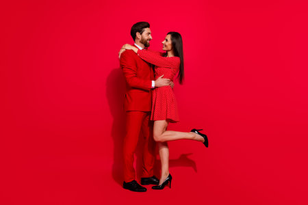 Full size profile photo of idyllic classy partners embrace look each other isolated on bright red color backgroundの写真素材