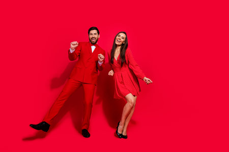 Full body photo of positive funky people enjoy dancing clubbing empty space isolated on red color backgroundの写真素材