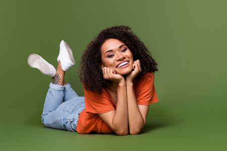Full length photo of cheerful positive lady dressed orange t-shirt arms cheeks relaxing isolated khaki color backgroundの写真素材