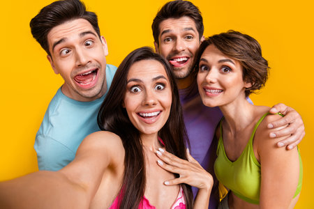 Photo of carefree positive people friends make selfie doing grimace face stick tongue out isolated...