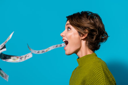 Profile side photo of cheerful girl wear stylish pullover clothes catch dollars casino jackpot empty space isolated cyan color backgroundの写真素材