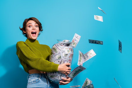 Photo of glad positive lady wear green clothes collect income money jar isolated on cyan color backgroundの写真素材