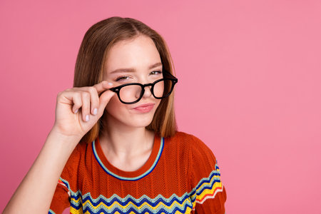 Photo of minded suspicious intelligent girl arm touch eyeglasses ponder empty space isolated on pink...